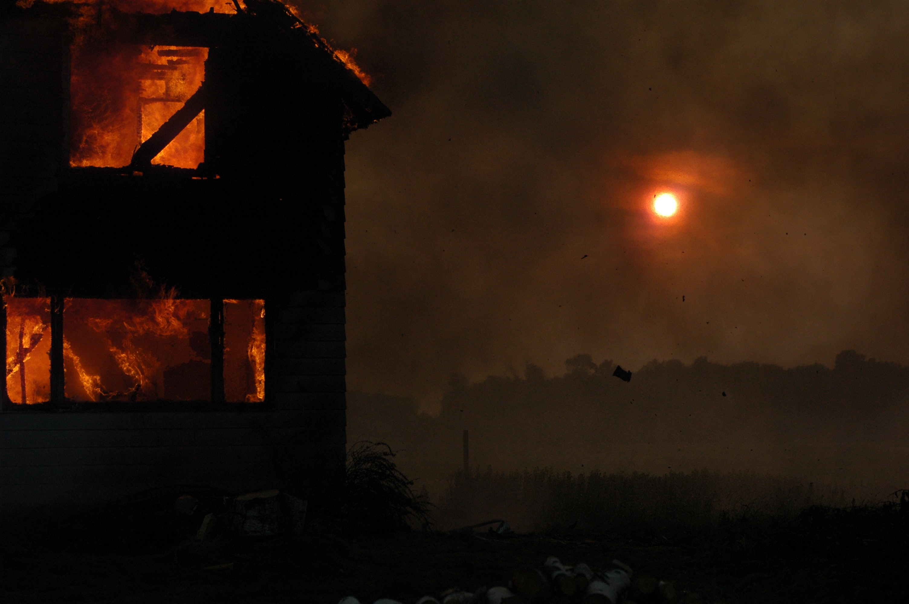 Burning house with sun bleeding through the smoke.