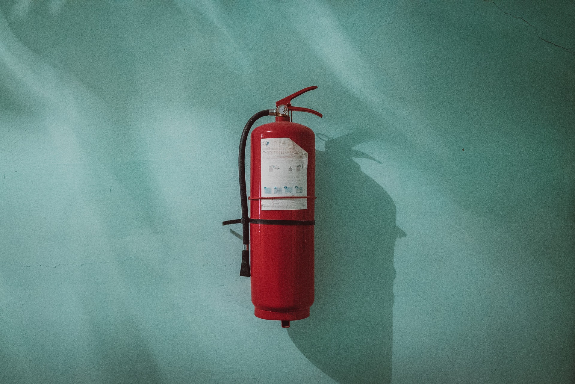 Close up of a fire extinguisher on a light green wall